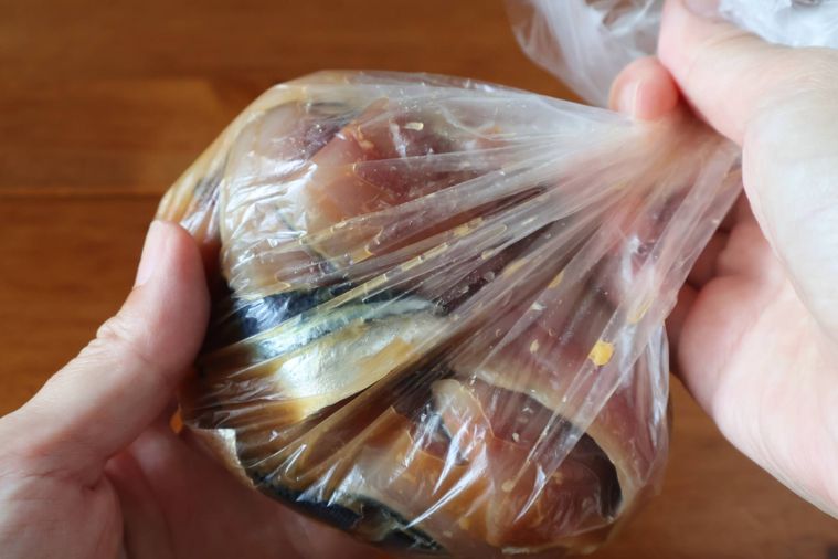 袋に入れたサンマをもみ込んでいる