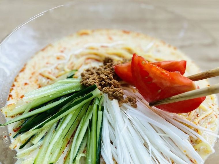 冷やし担々麺に野菜をトッピングしている様子