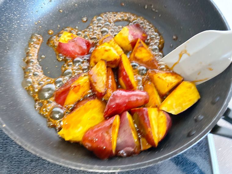 フライパンで焼いたさつまいもをたれに絡める様子
