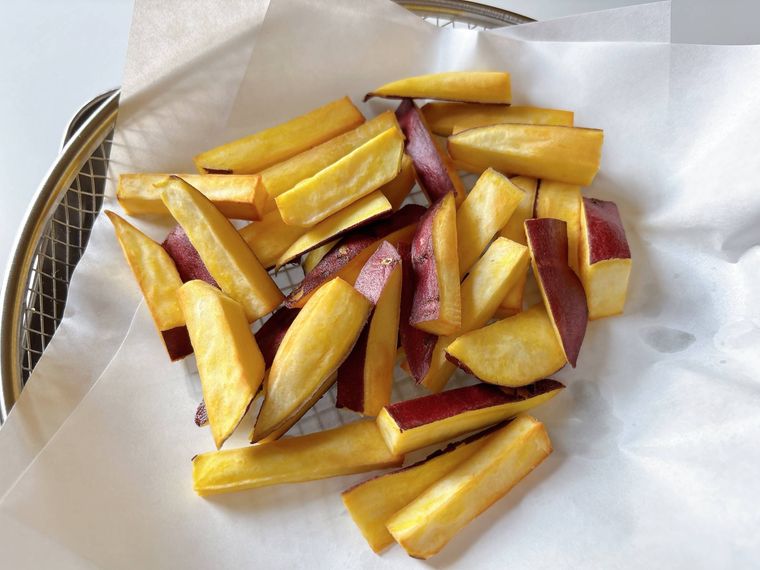 キッチンペーパーをしいた揚げ物バットにおかれた素揚げのさつまいも