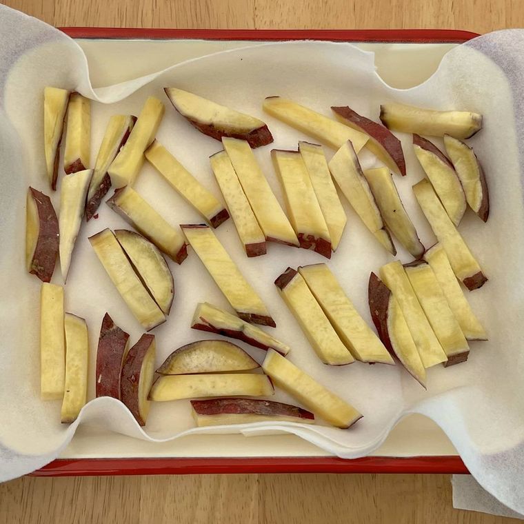 キッチンペーパーをひいたバットに並べられたスティック状に切られたさつまいも