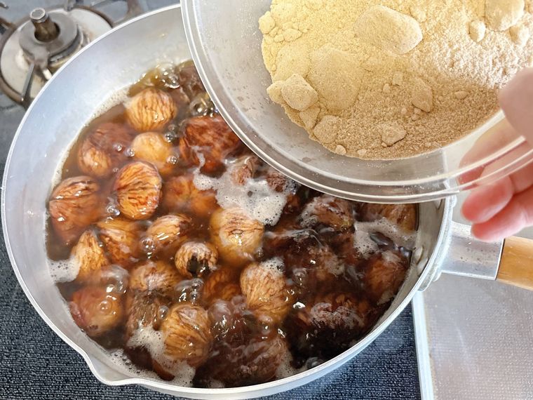 栗を煮る鍋にきび砂糖を加える様子