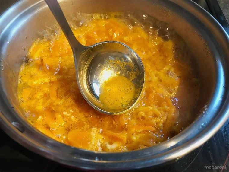 鍋の中のみかんからおたまでアクをとっている様子