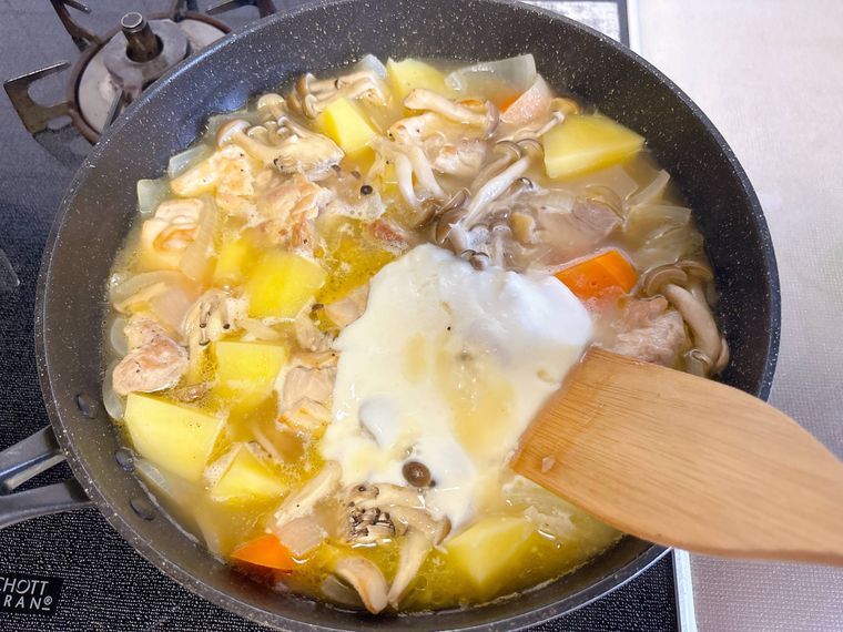 煮込んだフライパンにホワイトソースを加えた様子