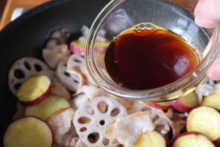 フライパンに調味料を加えている