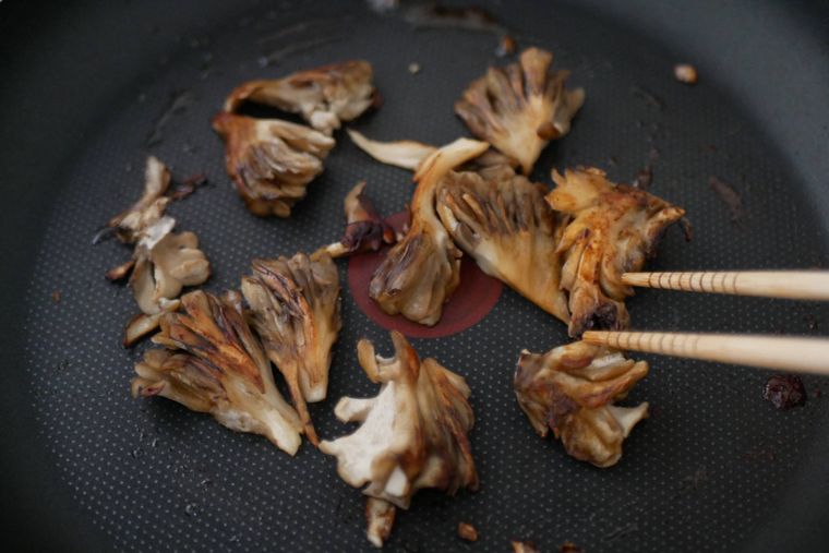 まいたけバターにしょうゆを入れ炒める様子