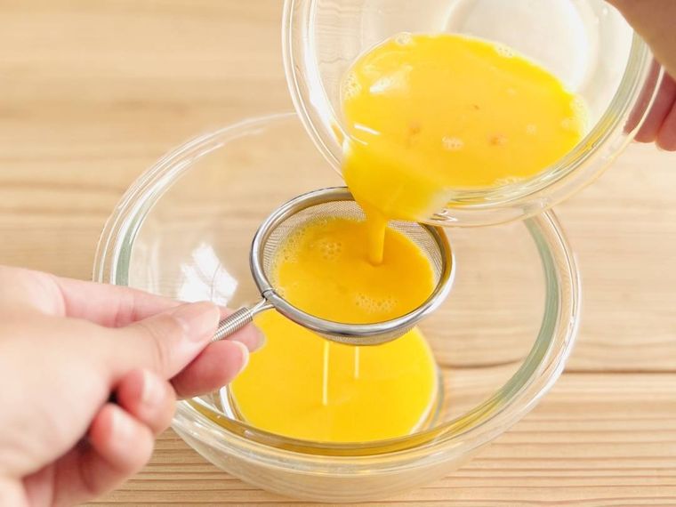 卵液を茶こしでこしている様子