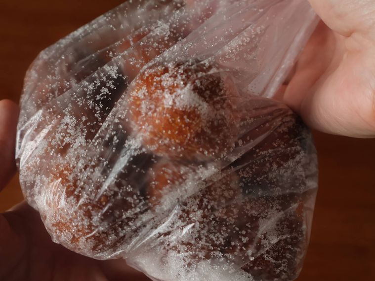 ドーナツを袋に入れてグラニュー糖をまぶしている