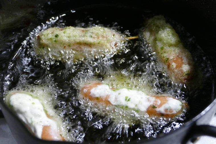 ウインナーソーセージを油鍋で揚げる様子