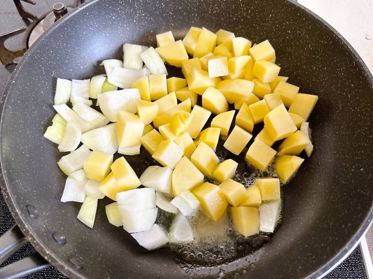 フライパンで玉ねぎとじゃがいもを炒める様子