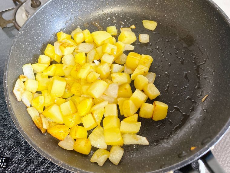 フライパンで玉ねぎとじゃがいもを炒める様子