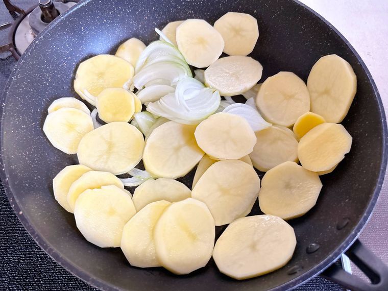 フライパンで玉ねぎとじゃがいもを炒める様子