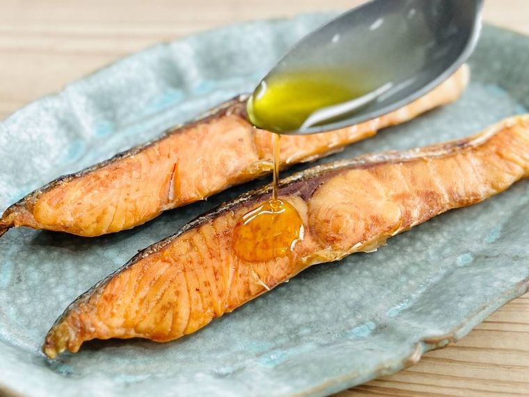 焼いた鮭にオリーブオイルをかけている様子