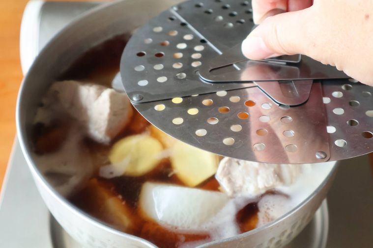 煮物の鍋に落とし蓋をしている