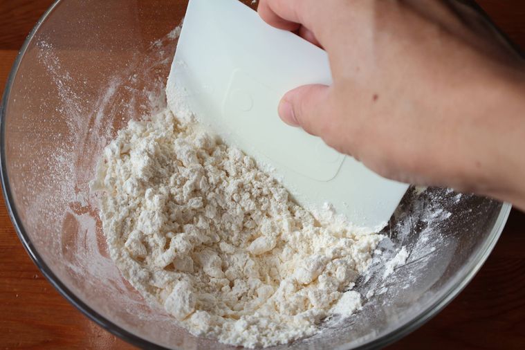 ボウルに入ったバターと粉をスケッパーで刻んでいる