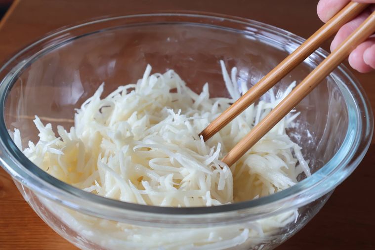 ボウルでせん切りのじゃがいもを混ぜている