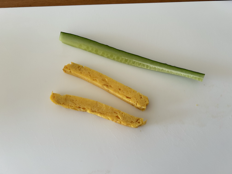 まな板の上に切られたきゅうりと卵焼きがのっている