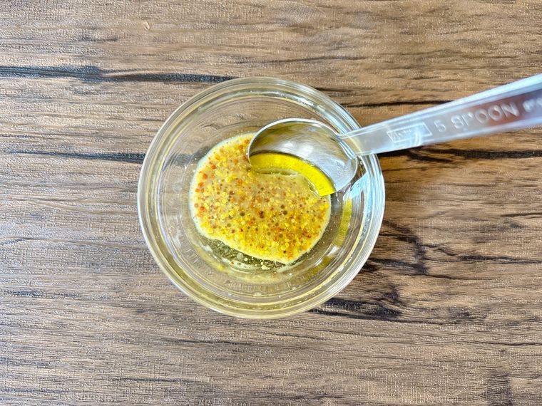 器で粒マスタードと穀物酢、オリーブオイルを混ぜる様子