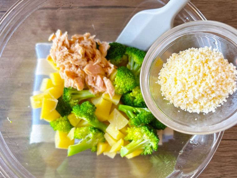 ブロッコリー、じゃがいもツナ缶が入ったボウルに粉チーズを加える様子