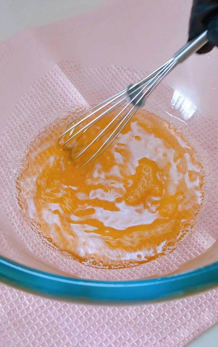 透明の耐熱ボウルの中で、泡立て器ではちみつとお湯を混ぜているところ