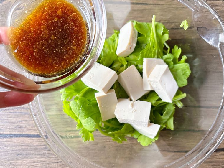 ボウルに入った春菊、木綿豆腐にドレッシングを加える様子