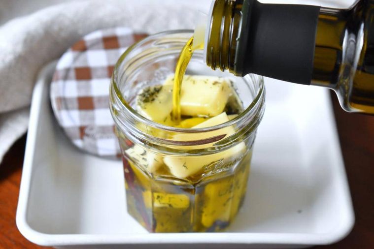 オリーブオイルを垂らした、チーズとハーブが入った瓶