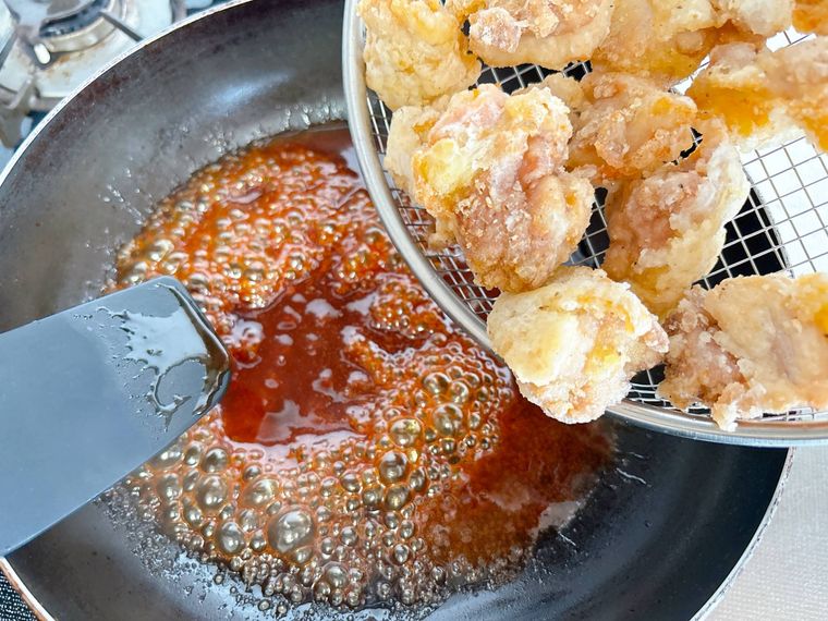 フライパンのヤンニョムだれに唐揚げを入れる様子