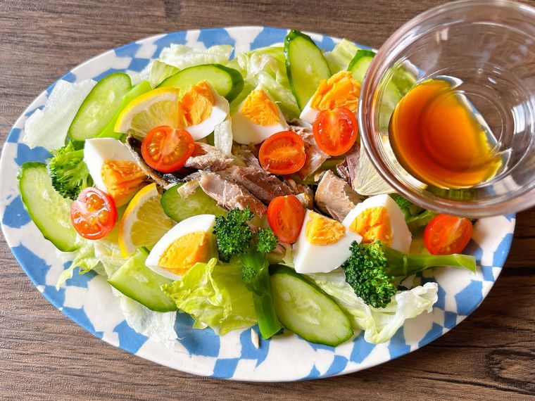 皿に盛り付けたサラダにポン酢しょうゆをかける様子