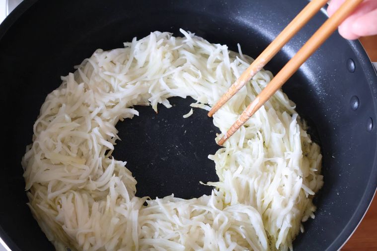 フライパンでせん切りのじゃがいもをリング状に焼いている