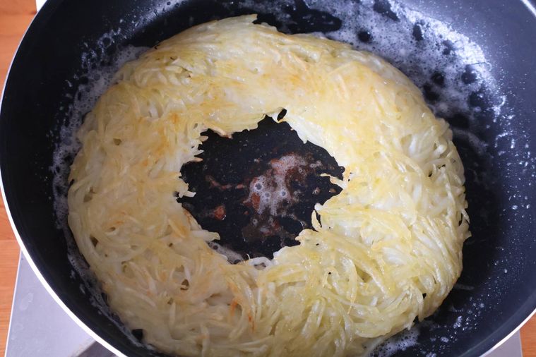 せん切りのじゃがいもにバターで焼き色をつけている