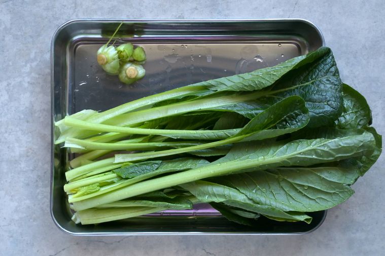 調理用バットの上に水洗いした小松菜と切り落とした根元部分が置いてある