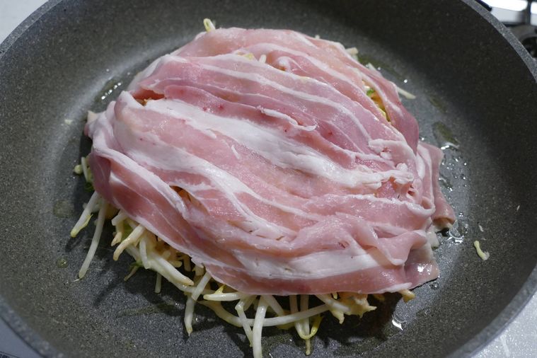 フライパンに生地を流し入れて豚バラ肉を重ねた様子