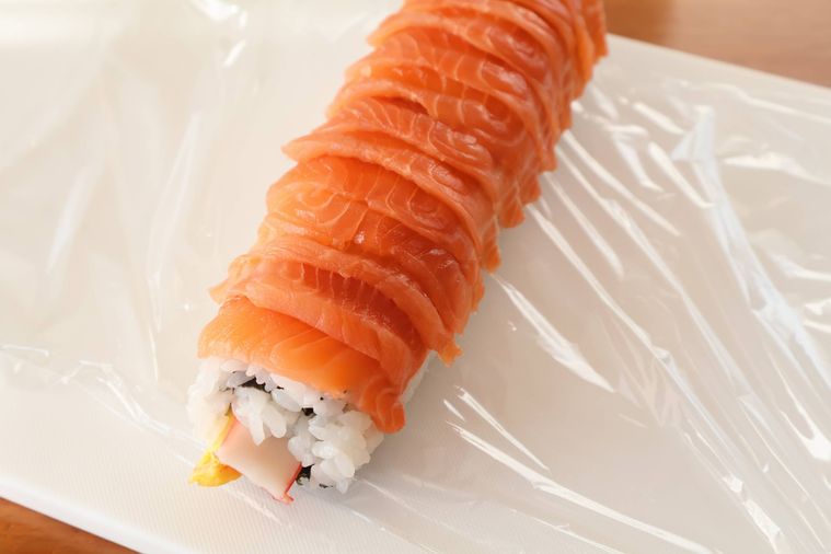 ロール寿司の上面にサーモンがのっている