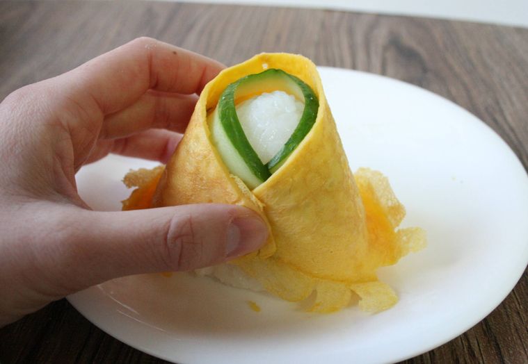 おにぎりにきゅうりと薄焼き卵を巻きつけている様子