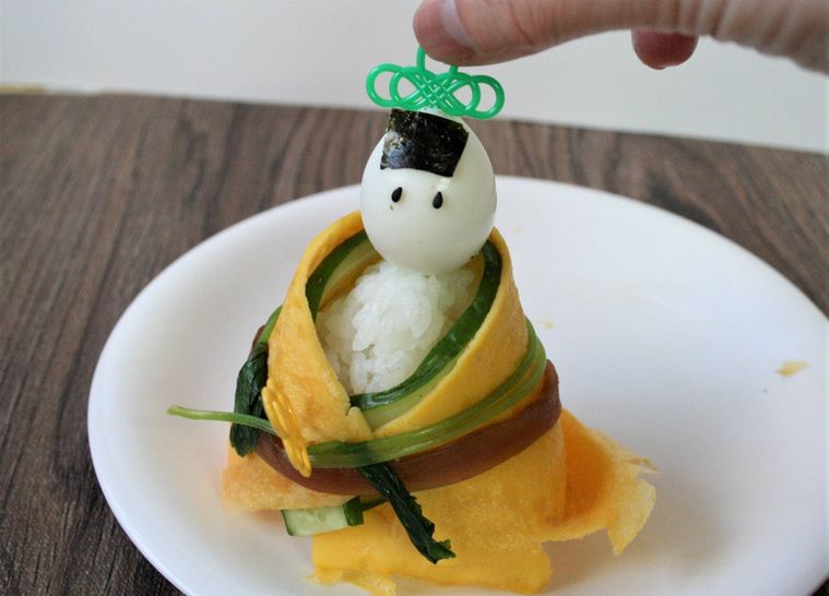 お雛様寿司の顔部分をつけている様子