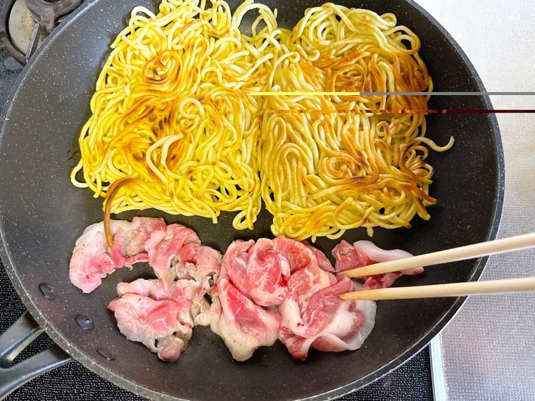 フライパンで中華麺、豚こま肉を焼く様子