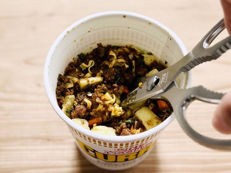 カップヌードル カレーの麺をキッチンバサミで刻んでいる様子