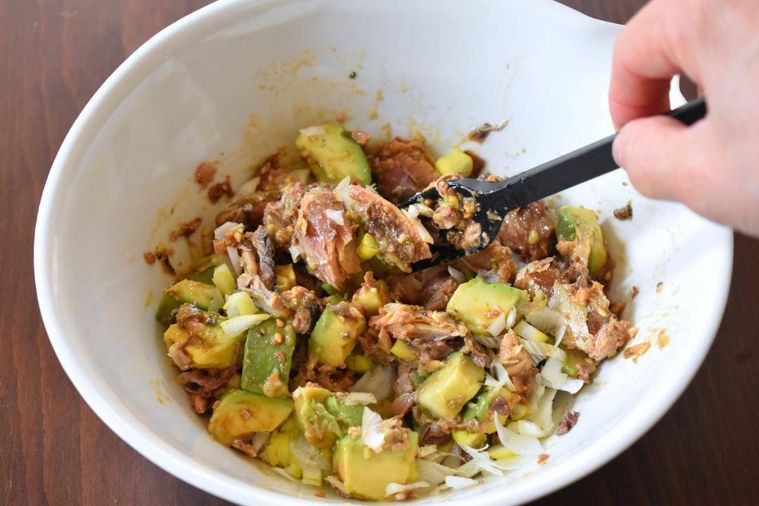 ボウルの中で調味料と混ぜたさば、アボカド、調味料