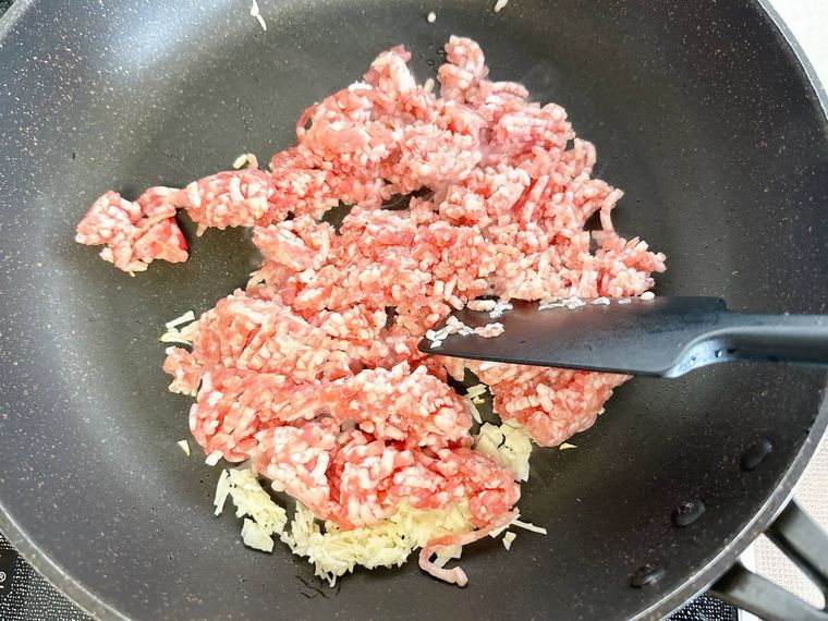 フライパンでにんにくと豚ひき肉を炒める様子