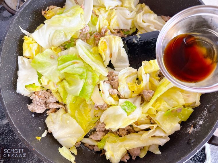 キャベツと豚ひき肉の炒め物に調味料を加える様子