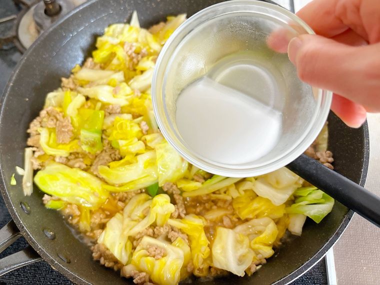 キャベツと豚ひき肉を煮たものに水溶き片栗粉を加える様子