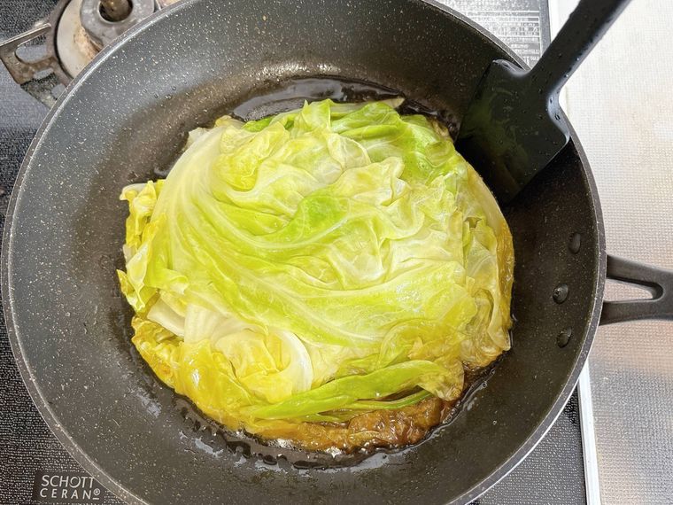 ゴムベラでフライパンに入った重ね蒸しの形を整える様子