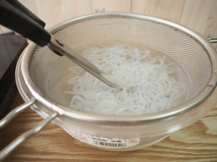 下ゆでしたしらたきをキッチンばさみで切る様子