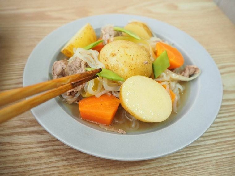 皿に盛った新じゃがの肉じゃがにさやえんどうを添える様子