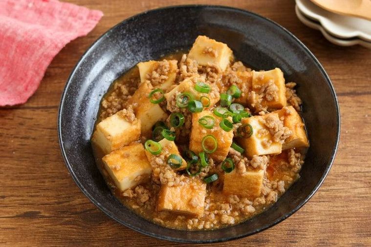 完成した厚揚げ麻婆を黒い器に盛る