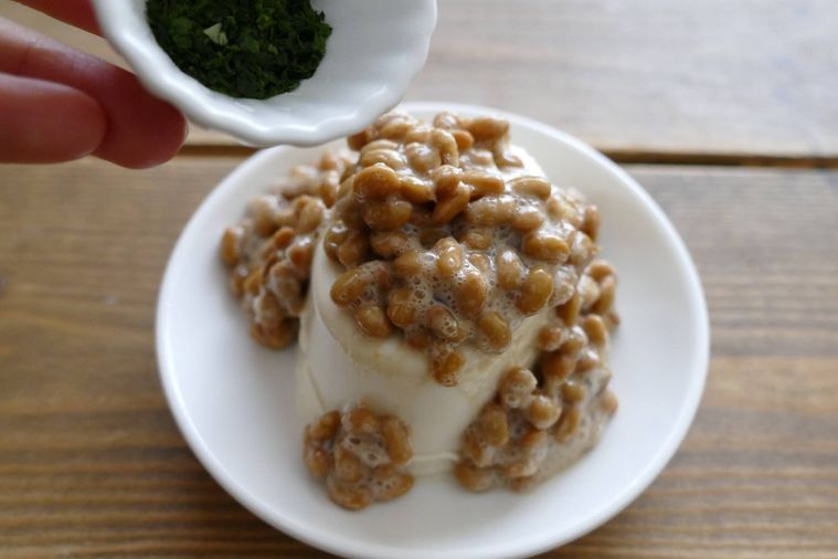 納豆をおかけた絹豆腐に青のりをかける様子