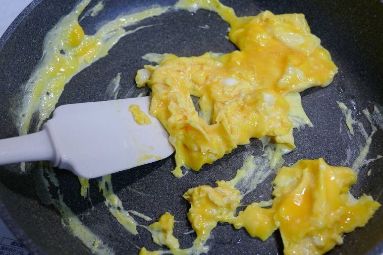フライパンで半熟卵をヘラで混ぜる様子