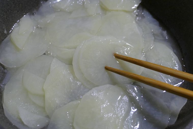 じゃがいもスライスを蒸し煮にして箸を刺してやわらかさを確かめる様子