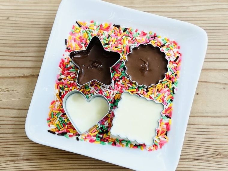 チョコスプレーの上に置いたクッキー型にチョコレートを流し込んだ様子