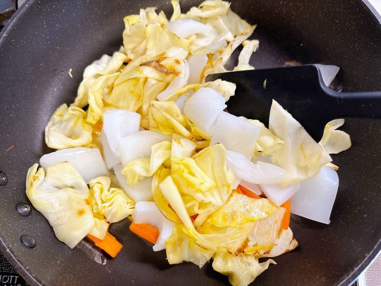 野菜にイカを加えて炒める様子